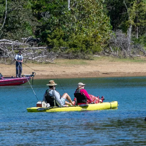 2 people peddle boating on Cherokee Lake with man fishing